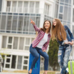 Deux étudiantes arrivent dans une résidence moderne à Orléans avec leurs valises, illustrant le dynamisme du marché de l'immobilier à Orléans.