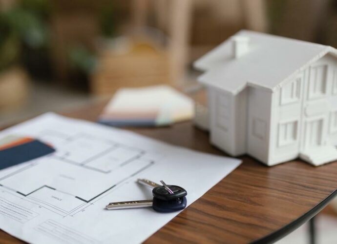 Plan immobilier avec clés et maquette de maison sur une table – agence immobilière à Fontainebleau