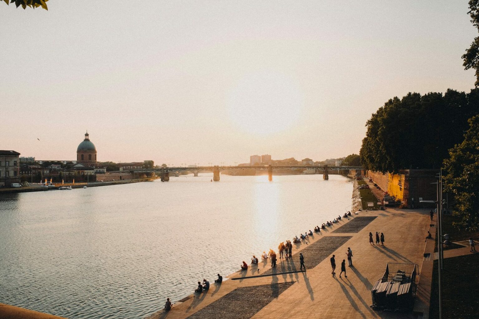 Coucher de soleil sur la Garonne avec promeneurs, idéal pour investir à Toulouse.