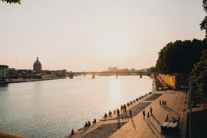 Coucher de soleil sur la Garonne avec promeneurs, idéal pour investir à Toulouse.