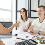 Un couple rencontre une agente dans un bureau lumineux pour choisir la meilleure agence immobilière à Avignon.