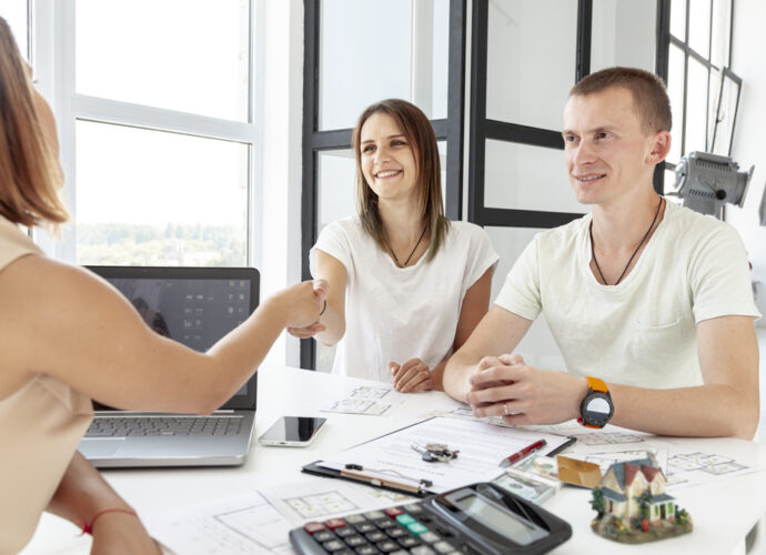Un couple rencontre une agente dans un bureau lumineux pour choisir la meilleure agence immobilière à Avignon.