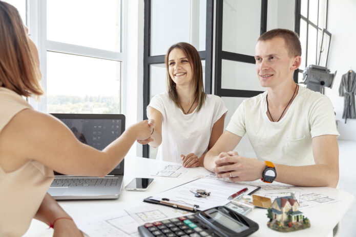 Un couple rencontre une agente dans un bureau lumineux pour choisir la meilleure agence immobilière à Avignon.