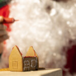 Maison en pain d'épices en construction, décorée pour Noël, représentant les rêves immobiliers des Français pendant les fêtes.