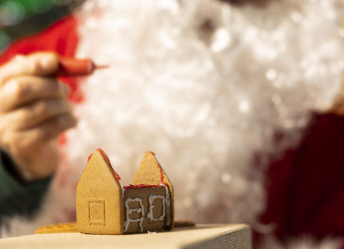Maison en pain d'épices en construction, décorée pour Noël, représentant les rêves immobiliers des Français pendant les fêtes.