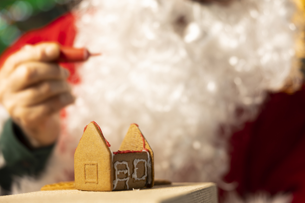 Maison en pain d'épices en construction, décorée pour Noël, représentant les rêves immobiliers des Français pendant les fêtes.
